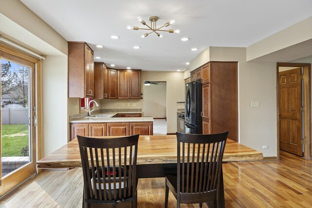 kitchen with light countertops, an inviting chandelier, light wood-style flooring, and freestanding refrigerator