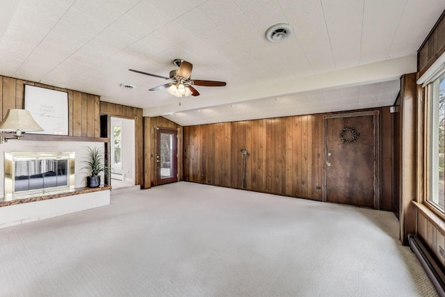 unfurnished living room featuring a baseboard radiator, wooden walls, a brick fireplace, and carpet flooring