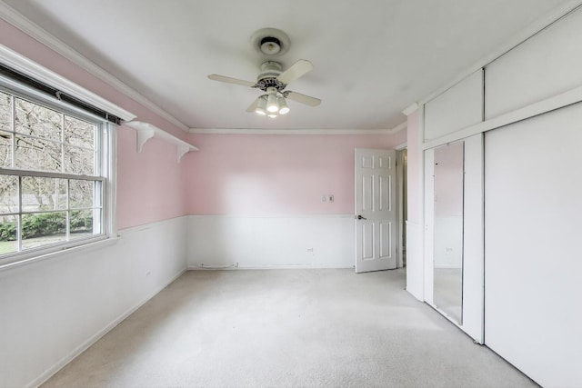 unfurnished bedroom with light carpet, a ceiling fan, a closet, and ornamental molding