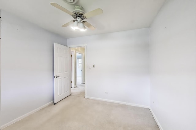 empty room with baseboards, a ceiling fan, and light colored carpet