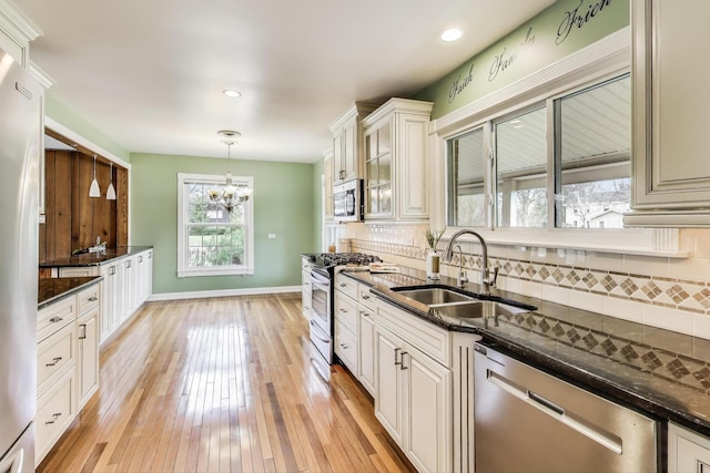 kitchen featuring a notable chandelier, decorative backsplash, appliances with stainless steel finishes, and a sink