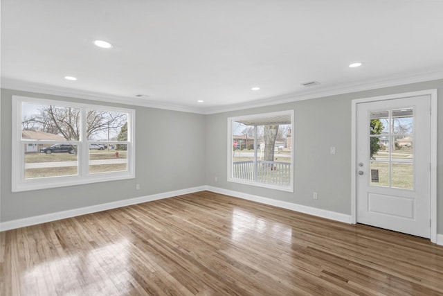 unfurnished living room featuring a wealth of natural light, crown molding, and baseboards