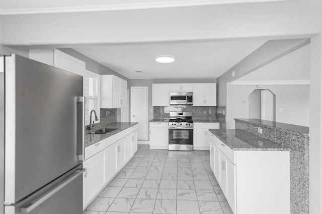 kitchen with a sink, decorative backsplash, marble finish floor, white cabinetry, and appliances with stainless steel finishes