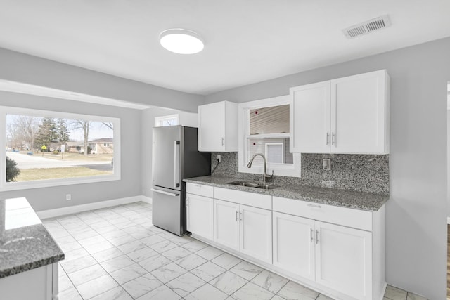 kitchen featuring white cabinets, marble finish floor, visible vents, a sink, and freestanding refrigerator