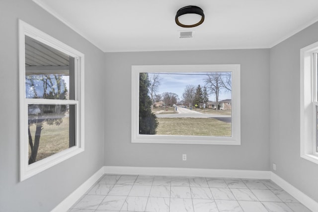 empty room with a wealth of natural light, marble finish floor, baseboards, and visible vents