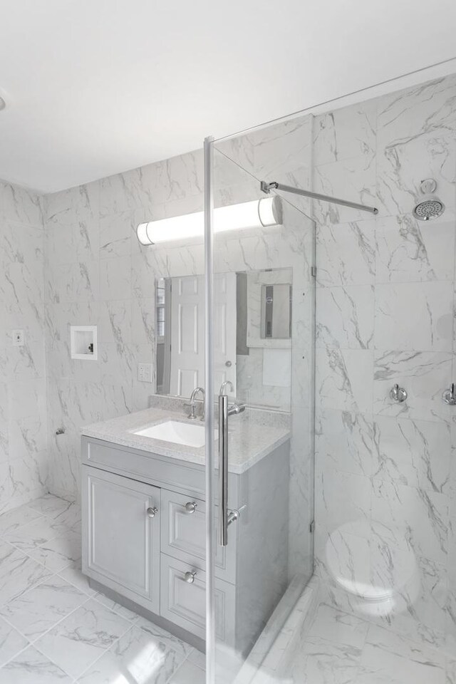 full bath with marble finish floor, vanity, and a marble finish shower