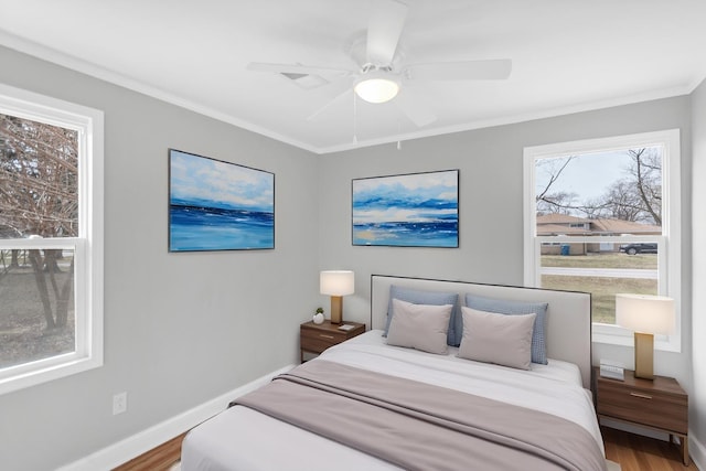bedroom with wood finished floors, crown molding, baseboards, and a ceiling fan