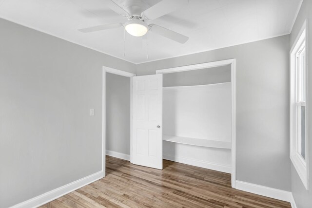 unfurnished bedroom with ceiling fan, baseboards, wood finished floors, and a closet