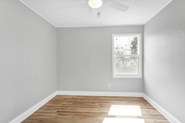 spare room with wood finished floors, crown molding, and baseboards