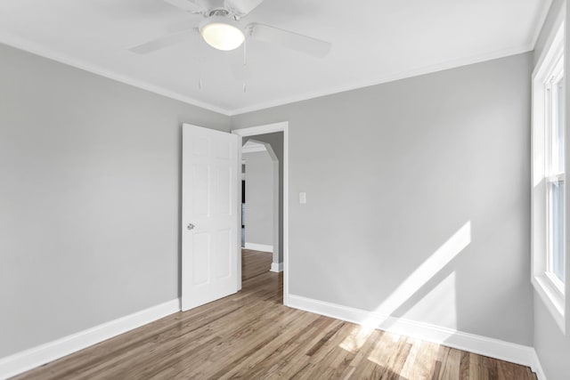 unfurnished room featuring baseboards, a ceiling fan, wood finished floors, and crown molding
