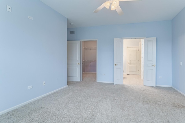 unfurnished bedroom with a spacious closet, visible vents, a closet, baseboards, and carpet flooring