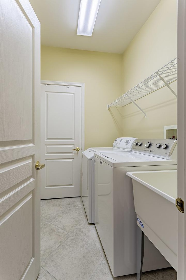 washroom featuring washer and clothes dryer, laundry area, and light tile patterned floors