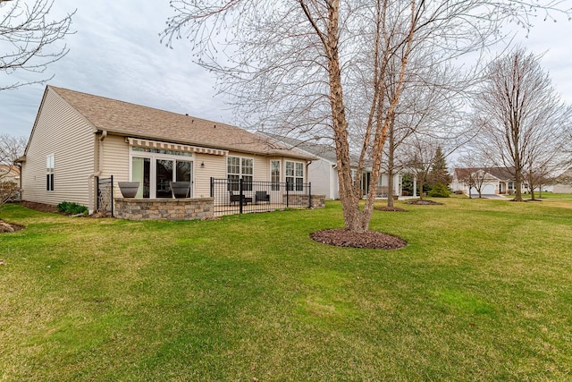 back of property with a lawn, a shingled roof, a patio, and fence