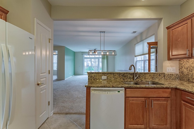 kitchen with a peninsula, a sink, visible vents, white appliances, and brown cabinets