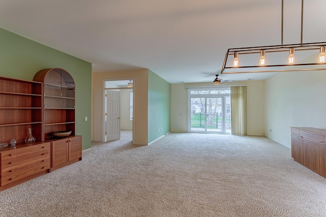unfurnished living room featuring baseboards, a ceiling fan, and carpet flooring