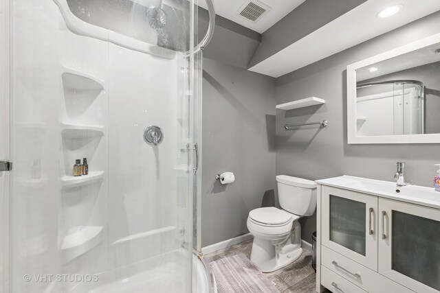 full bath with vanity, toilet, baseboards, a shower stall, and visible vents