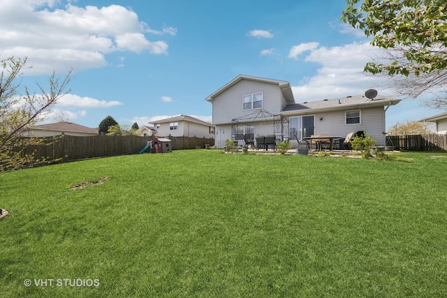 back of property featuring a yard, a patio, a fenced backyard, and a playground