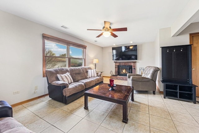 living area featuring light tile patterned flooring, ceiling fan, a fireplace, baseboards, and visible vents