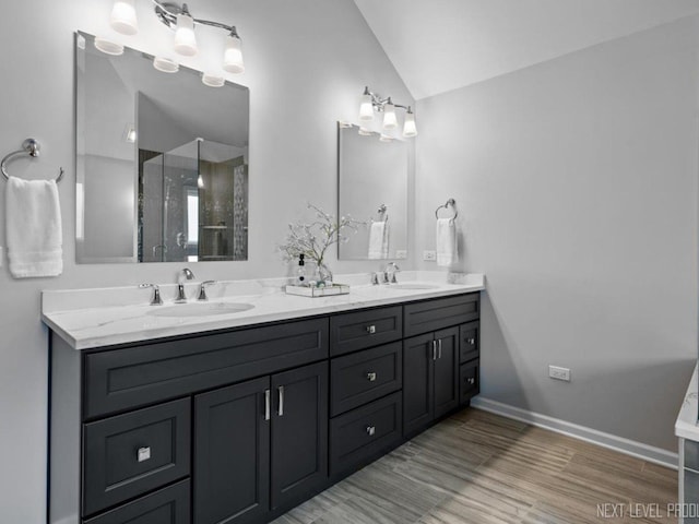 bathroom with double vanity, vaulted ceiling, a sink, and wood finished floors