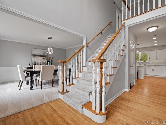 stairway with crown molding, baseboards, and wood finished floors