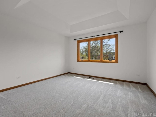 carpeted empty room featuring baseboards, visible vents, and a tray ceiling