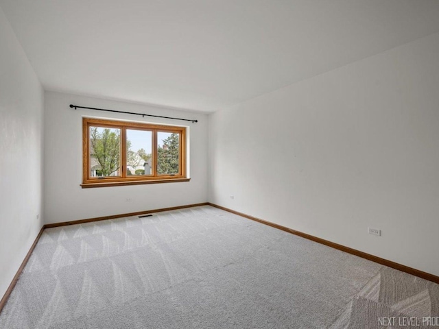 spare room featuring light colored carpet, baseboards, and visible vents
