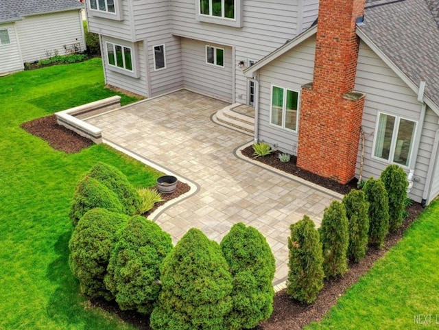 back of house with a lawn, a patio area, and a chimney