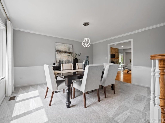 dining room with baseboards, ornamental molding, light carpet, and visible vents
