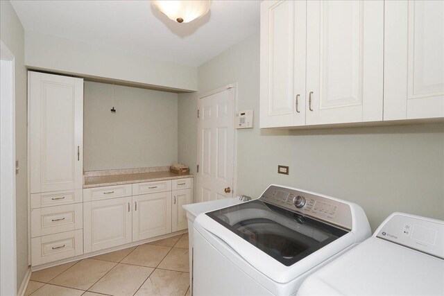 laundry room featuring cabinet space, washer and clothes dryer, and light tile patterned floors