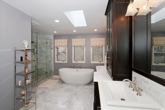 full bath with a soaking tub, recessed lighting, a skylight, marble finish floor, and a shower stall