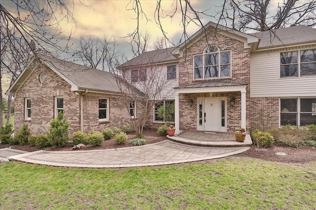 back of house featuring a lawn and brick siding