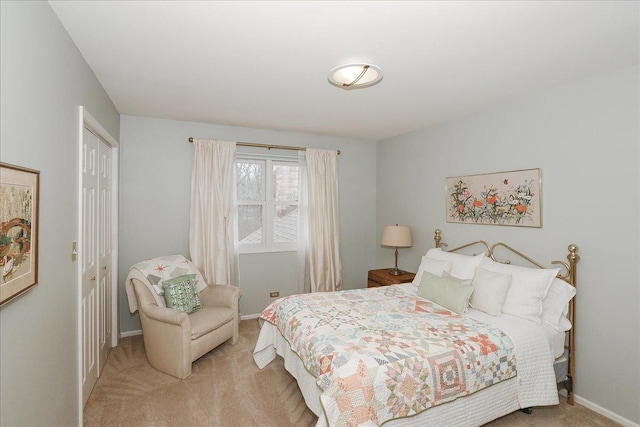 bedroom featuring baseboards, a closet, and light colored carpet