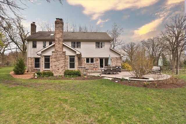 back of property with a yard, a chimney, and a patio