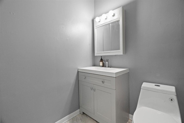 bathroom featuring vanity, toilet, baseboards, and marble finish floor