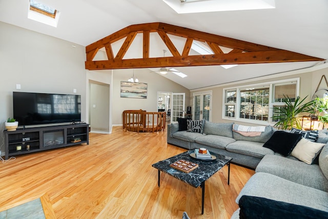 living room featuring vaulted ceiling with skylight, wood finished floors, a ceiling fan, and baseboards