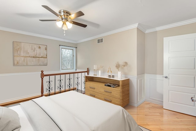 bedroom with a ceiling fan, ornamental molding, light wood finished floors, and visible vents