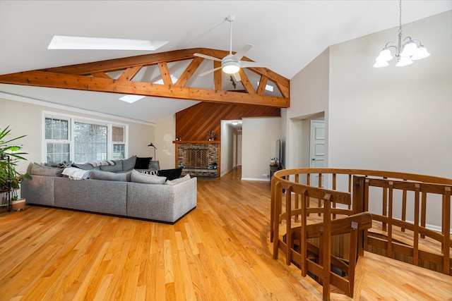 living room with high vaulted ceiling, light wood-style flooring, ceiling fan with notable chandelier, and a skylight