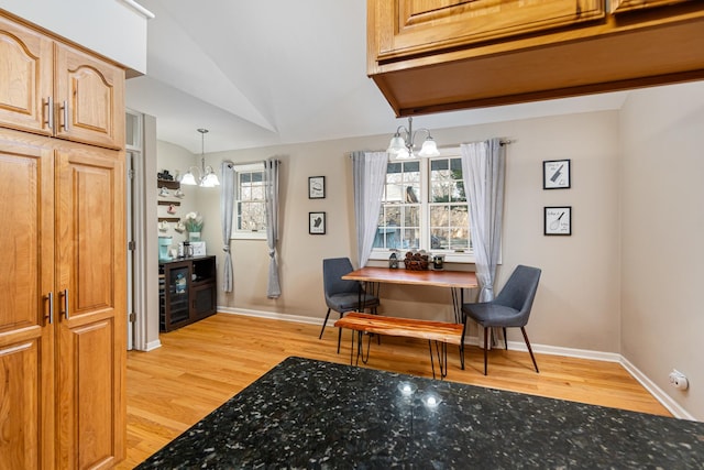 dining room featuring light wood-type flooring, a healthy amount of sunlight, baseboards, and a notable chandelier