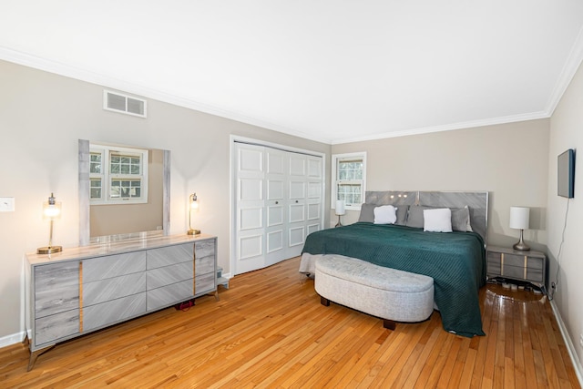 bedroom with crown molding, a closet, light wood-style flooring, baseboards, and visible vents