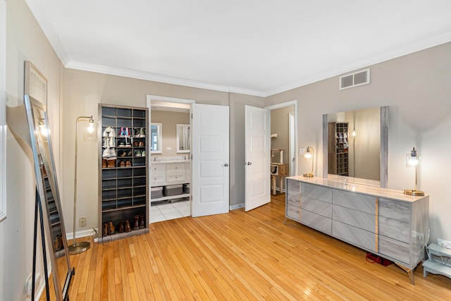 bedroom with light wood-style floors, baseboards, ensuite bath, ornamental molding, and visible vents