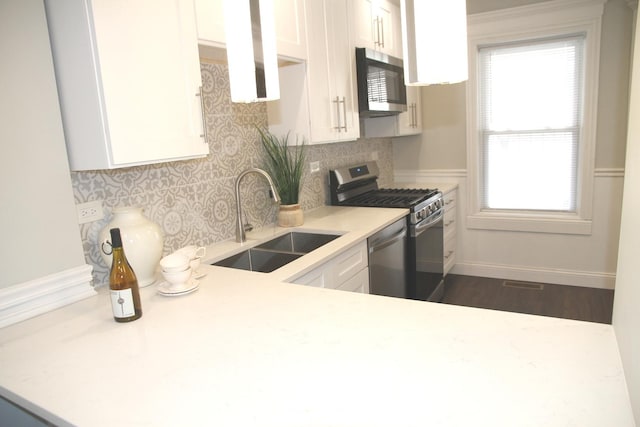 kitchen with light countertops, appliances with stainless steel finishes, white cabinetry, and a sink