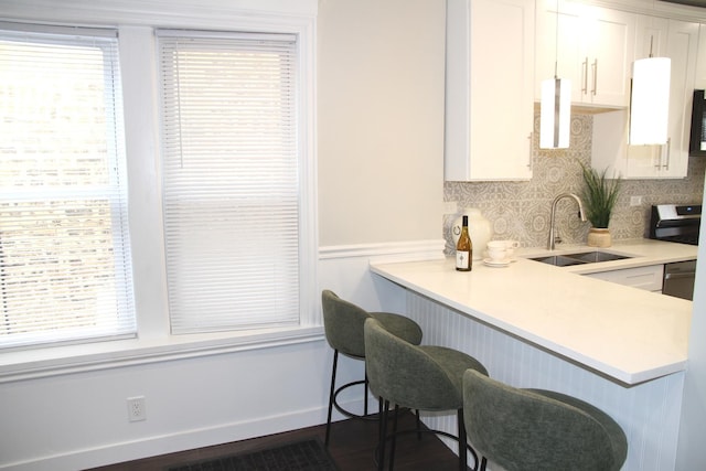 kitchen with a sink, backsplash, a kitchen bar, white cabinetry, and light countertops