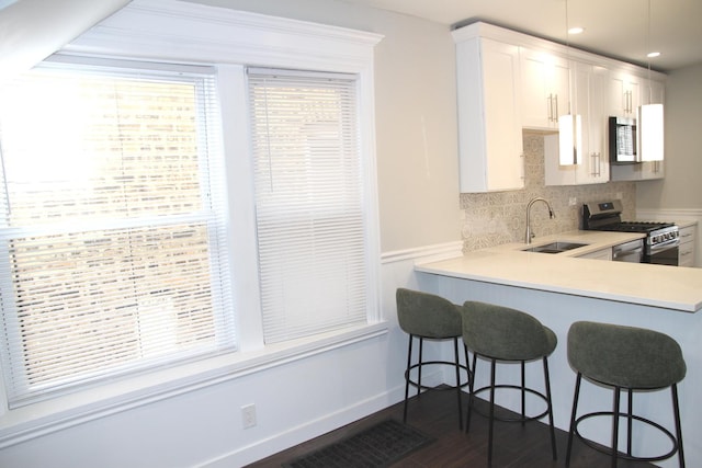 kitchen with stainless steel appliances, a sink, tasteful backsplash, a kitchen bar, and light countertops
