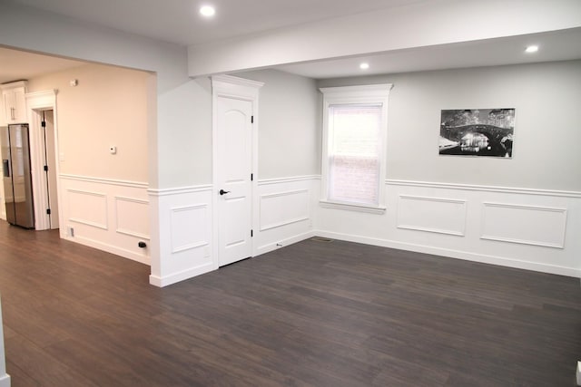 below grade area with dark wood finished floors, stainless steel fridge with ice dispenser, and recessed lighting
