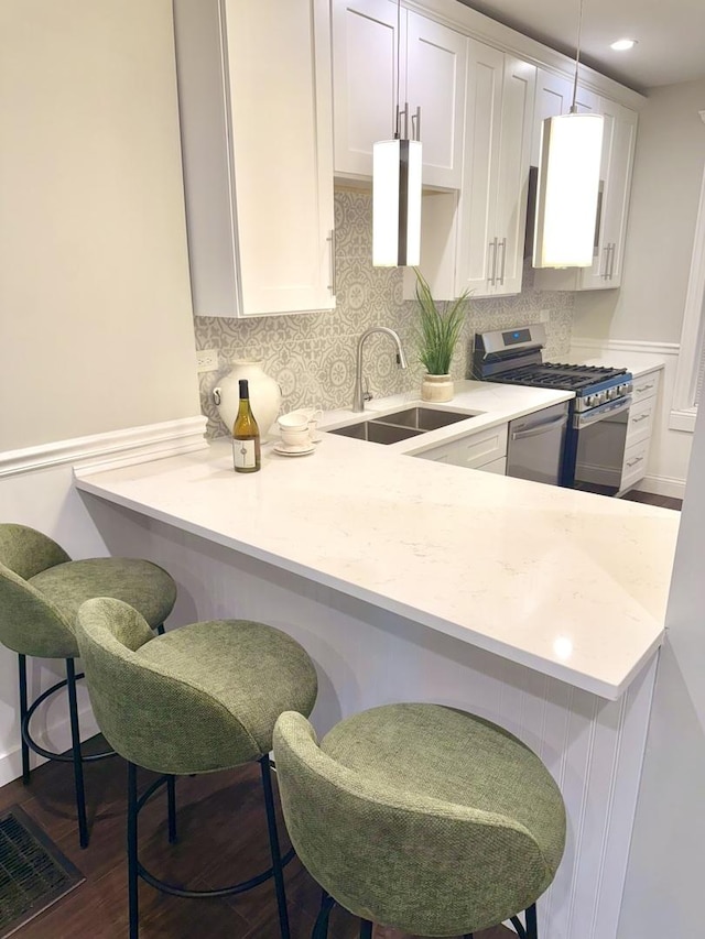 kitchen featuring a sink, white cabinetry, backsplash, appliances with stainless steel finishes, and visible vents