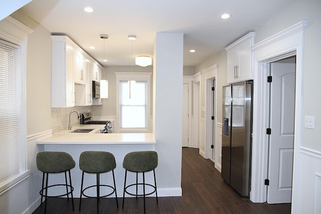 kitchen featuring stainless steel appliances, a kitchen breakfast bar, a sink, and dark wood finished floors