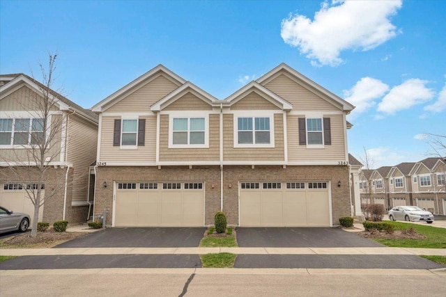 townhome / multi-family property with driveway, a garage, and brick siding