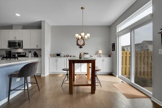dining space featuring a chandelier, baseboards, and light wood-style floors
