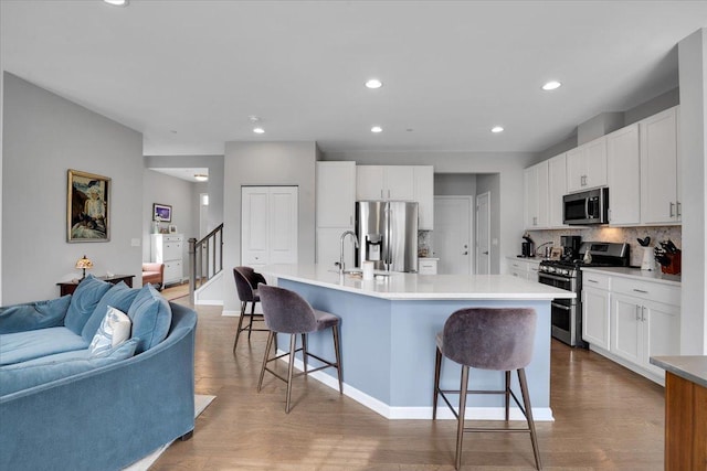 kitchen featuring tasteful backsplash, a sink, appliances with stainless steel finishes, a breakfast bar, and open floor plan