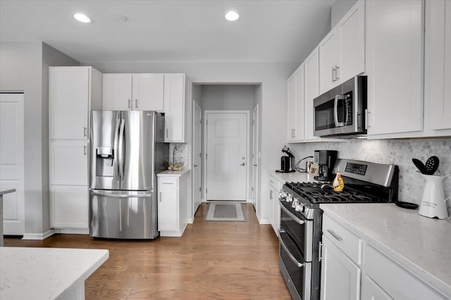 kitchen featuring recessed lighting, white cabinets, appliances with stainless steel finishes, and decorative backsplash